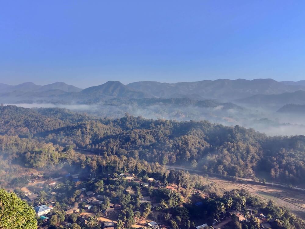 Berglandschaft in Nordthailand mit Morgennebel über Wäldern und Dörfern.